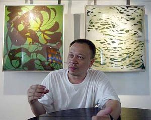 Sabri with his works titled 'Senjakan Berulang' (left) and 'Enggan Untuk Pulang.'