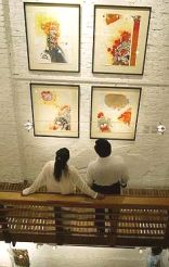 Guests appreciating the paintings at the exhibition.